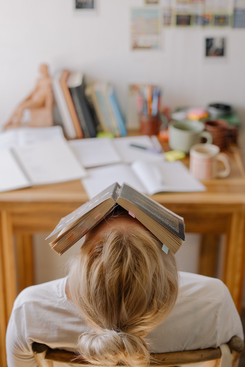 student with book on her face