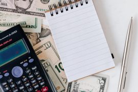 calcutator, note pad and dollar bills