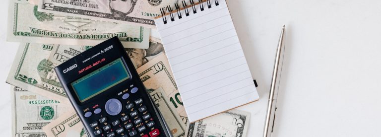 calcutator, note pad and dollar bills