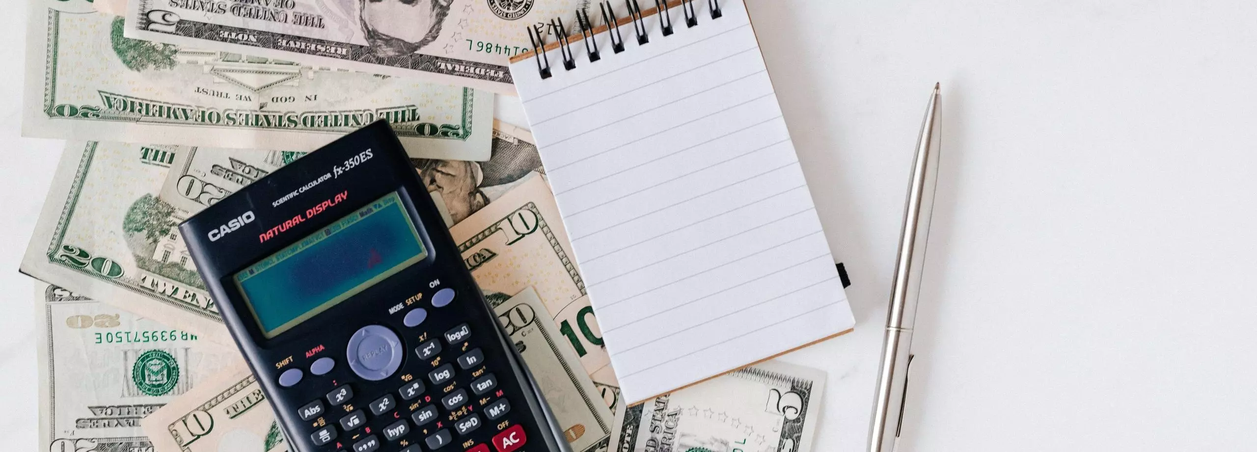 calcutator, note pad and dollar bills