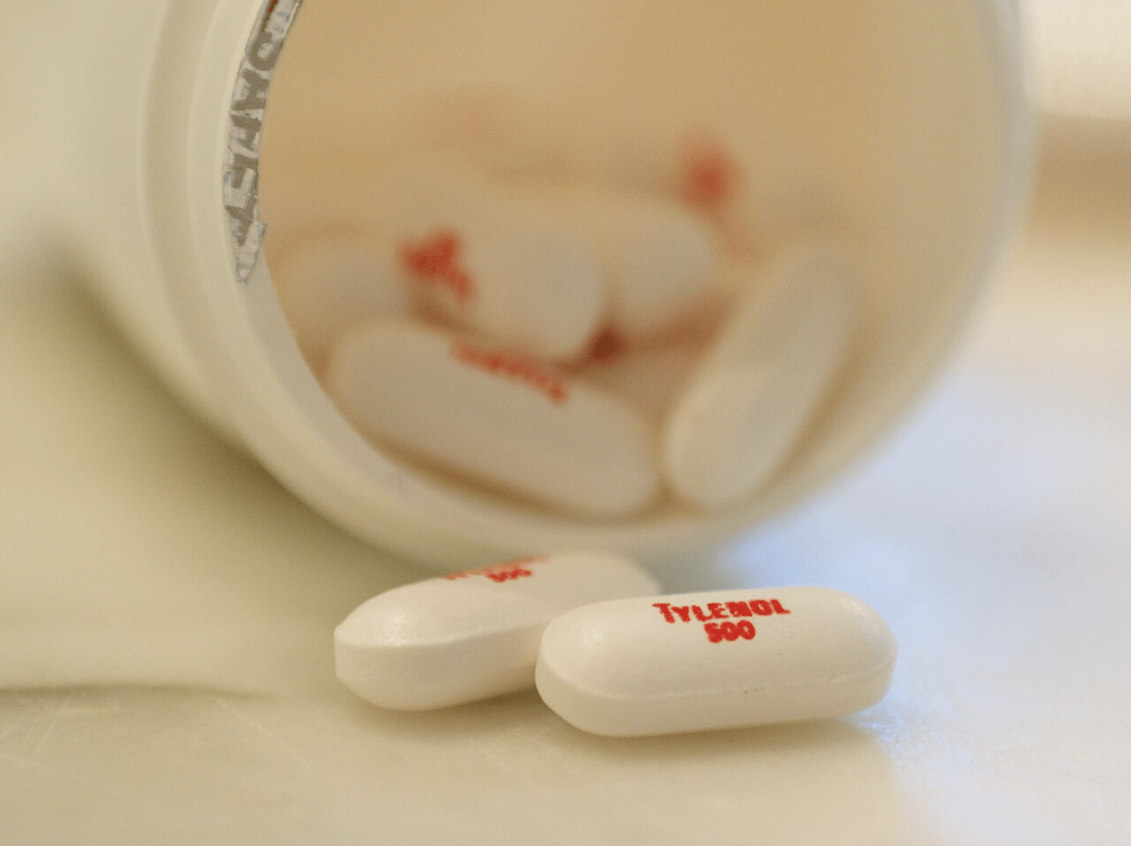 Three tylenol 500 mg tablets on a white surface with red tylenol text visible