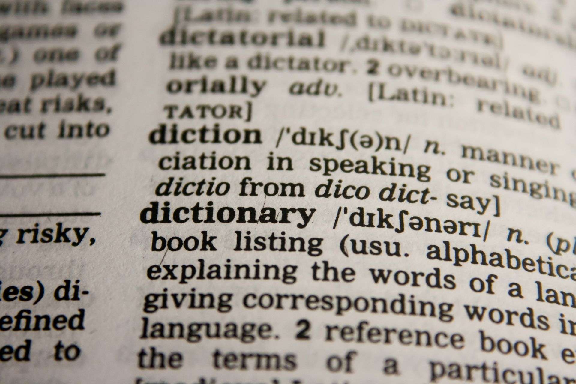 Close up of a dictionary page focusing on the word 'dictionary' with its pronunciation and definition visible